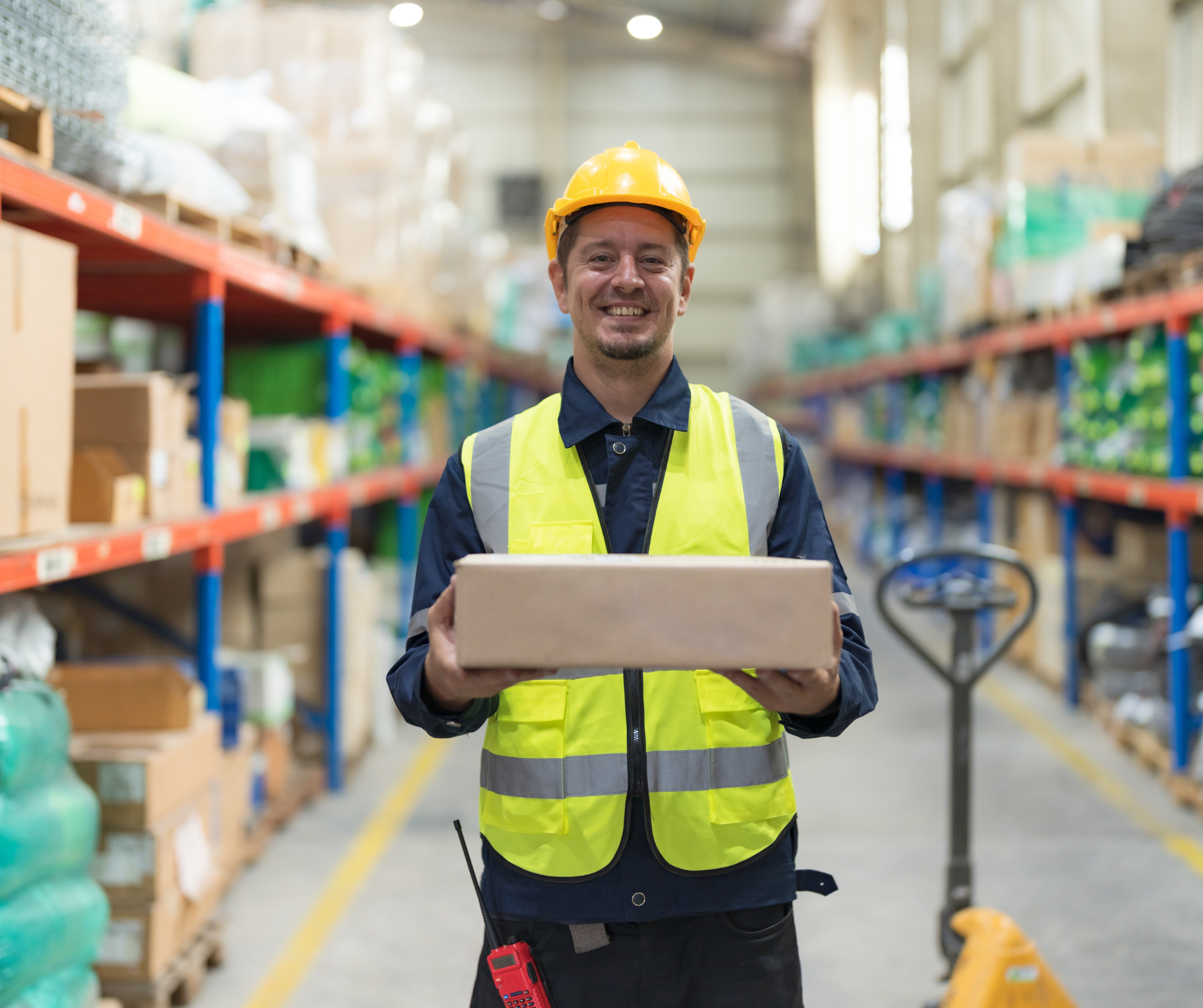 Worker with a box standing in a warehouse smiling