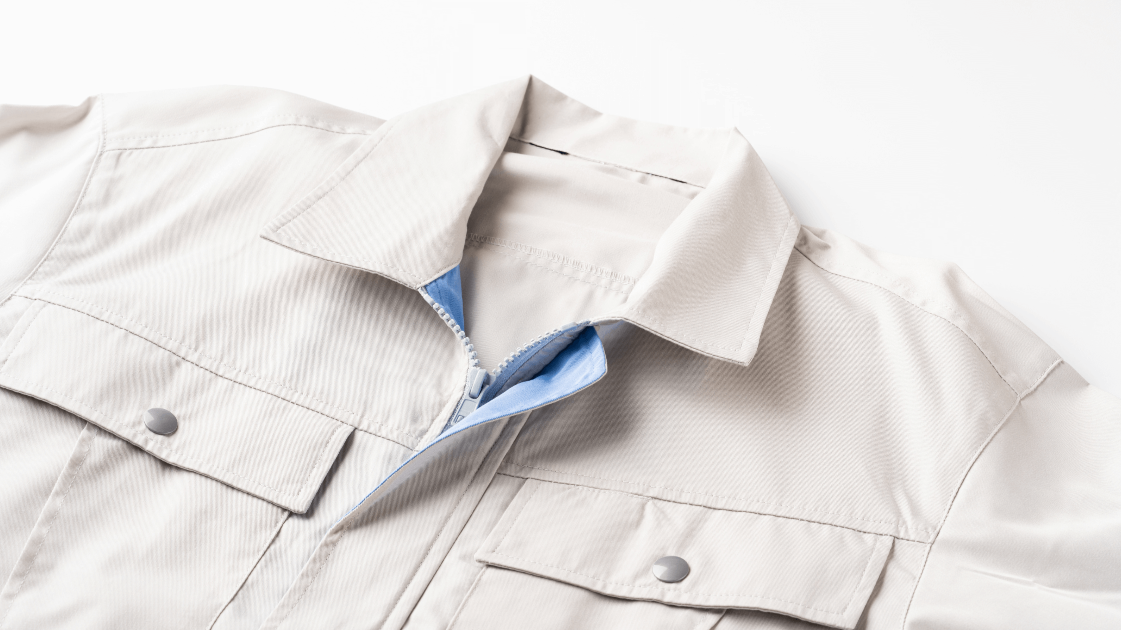 A close-up of a neatly folded, light-colored professional jacket with a blue interior zipper, symbolizing prepared and high-quality corporate uniforms and seasonal workwear.
