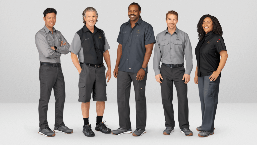 A diverse group of employees wearing well-fitted, professional uniforms and branded apparel, representing a team dressed in high-quality corporate uniforms from a trusted uniform provider.
