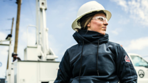 Utility worker wearing a Bulwark Women's FR Fleece Full Zip Hoodie, an NFPA 2112 compliant flame resistant jacket for cold weather