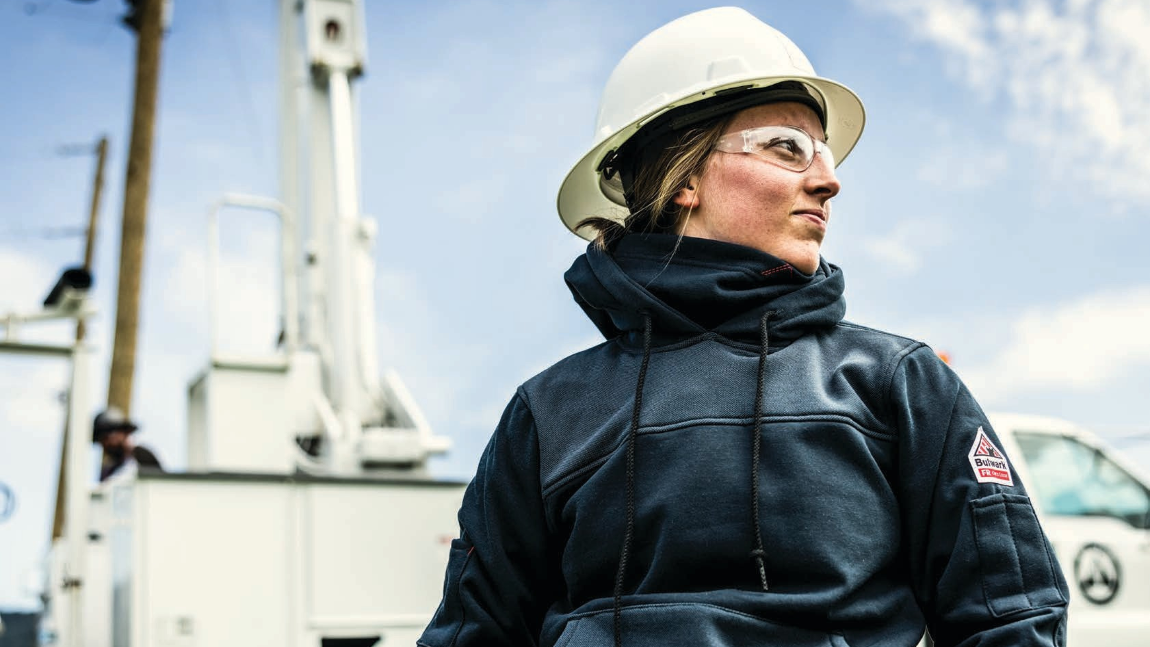 Utility worker wearing a Bulwark Women's FR Fleece Full Zip Hoodie, an NFPA 2112 compliant flame resistant jacket for cold weather